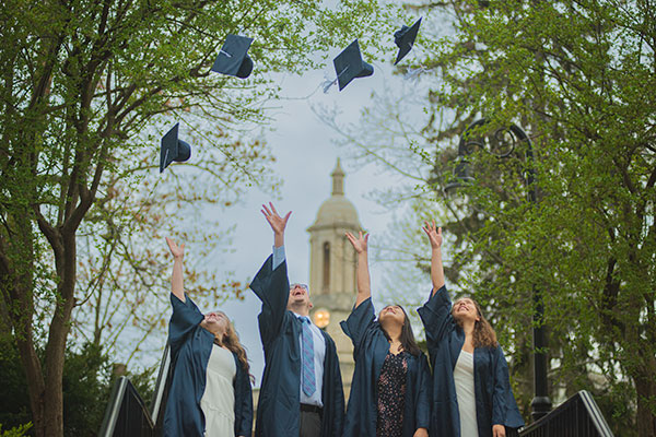 Penn State Commencement: Graduates in front of old main building tossing their caps.